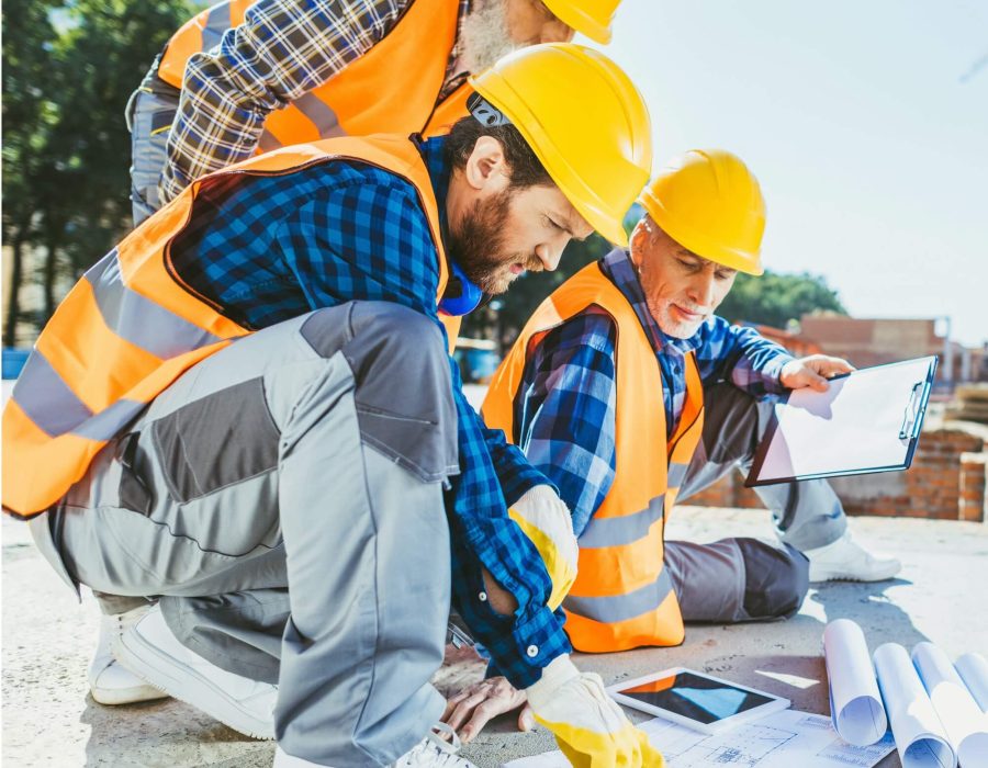 handsome-construction-workers-sitting-on-concrete-at-construction-site-discussing-building-plans-1.jpg